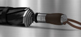 A zoomed in photo of the premium umbrella mostly showing the leather grip of the handle. It also shows the silver trim and the open and close button mechanism.
